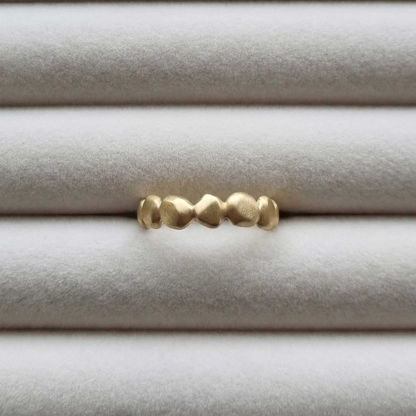 Gold ring with textured design on a light gray background