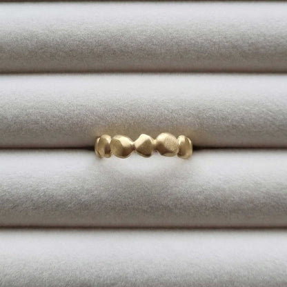Gold ring with textured design on a light gray background