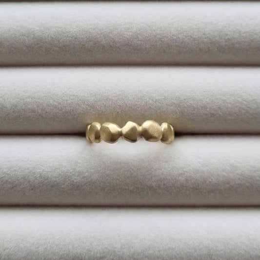 Gold ring with textured design on a light gray background
