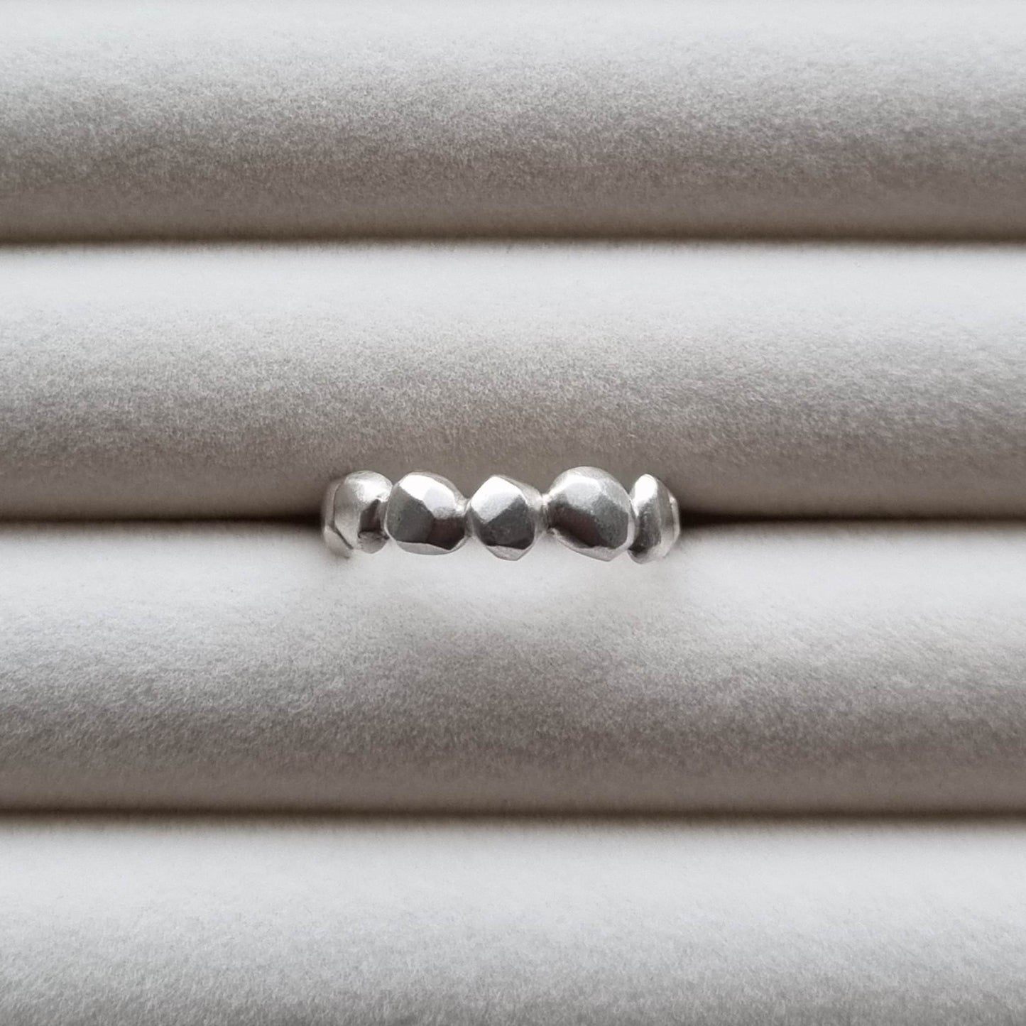 Silver ring with a textured band on a light gray background