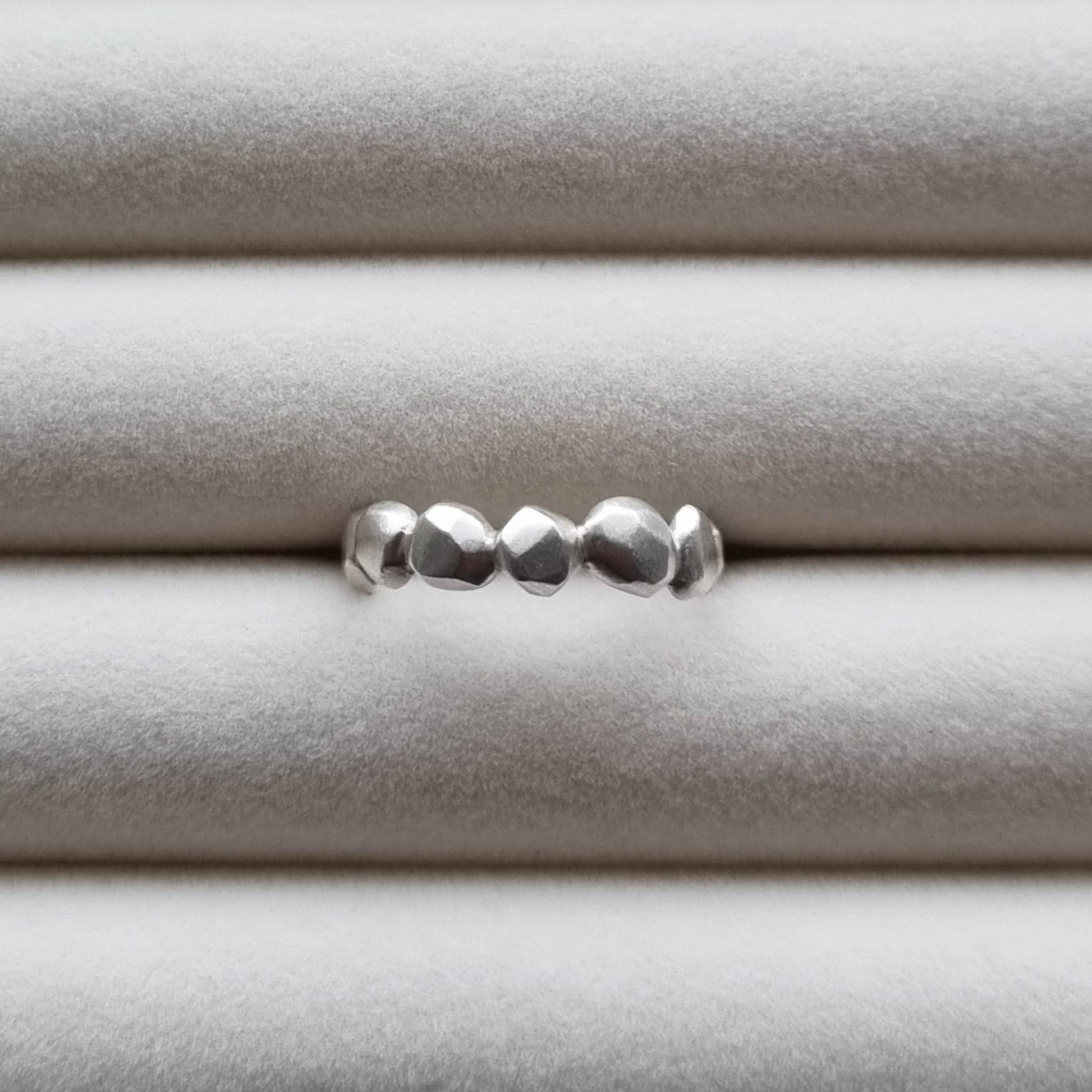 Silver ring with a textured band on a light gray background