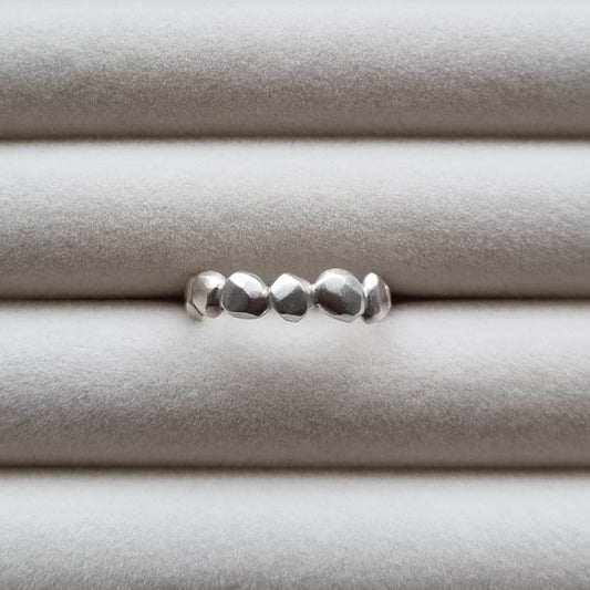 Silver ring with a textured band on a light gray background