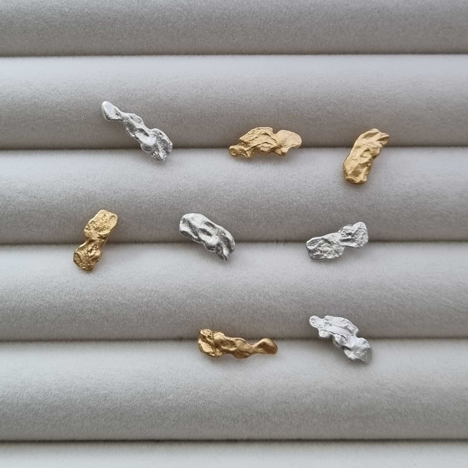 Gold and silver earrings on a textured gray surface